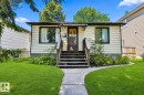Single-story residence featuring light-colored horizontal siding, dark window trim, and a dark entry door - 8318 80 Avenue, Edmonton, AB 