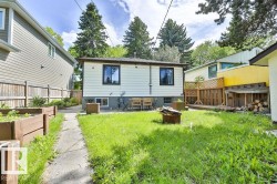 Rear exterior featuring white horizontal siding, black-framed windows, and a concrete patio - 