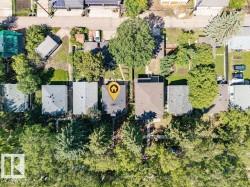 Aerial overview showcasing a property with a grey shingle roof and mature trees - 