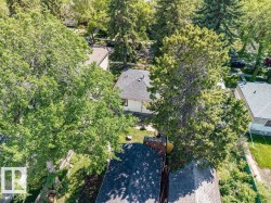 Residential property with a dark shingle roof, surrounded by mature trees - 