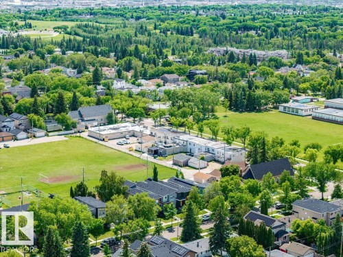 Aerial view showcasing expansive grounds with mature tree-lined perimeter, multiple residential structures, manicured lawn areas, and established landscaping - 8318 80 Avenue Nw, Edmonton, AB - Outdoor With View
