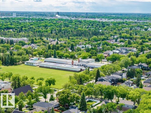 Expansive green space bordered by a large institutional building with a flat roof and numerous windows - 8318 80 Avenue Nw, Edmonton, AB - Outdoor With View
