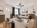 Bright living area featuring wood-finish flooring, a contemporary ceiling fan, and a neutral color palette - 8318 80 Avenue, Edmonton, AB 