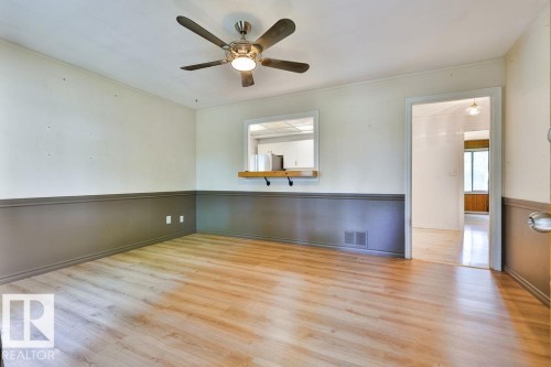 Spacious interior room featuring wood-finish flooring, two-tone wall treatment, and a ceiling fan with integrated lighting - 8318 80 Avenue, Edmonton, AB 