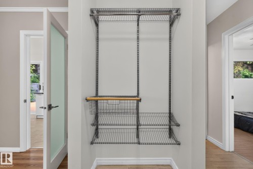 Custom wire shelving system featuring multiple shelves, two hanging rods, and an integrated basket drawer with a wood-finish handle - 12952 114 Street Nw, Edmonton, AB 