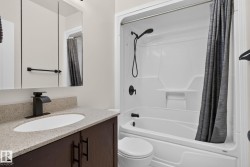 Bathroom featuring a dark wood-finish vanity with a light-toned countertop, an undermount sink, and a black faucet - 