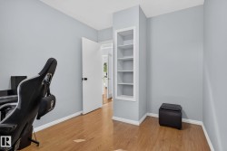 Room featuring wood-finish flooring, light gray wall paint, white baseboards, and a built-in recessed shelving unit - 