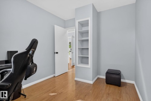 Room featuring wood-finish flooring, light gray wall paint, white baseboards, and a built-in recessed shelving unit - 12952 114 Street Nw, Edmonton, AB 
