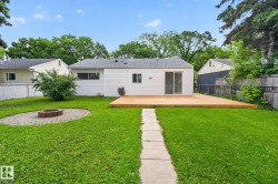 Expansive backyard featuring a central lawn, a paver patio with a fire pit, a concrete stepping stone path, a spacious wood deck, and white siding - 