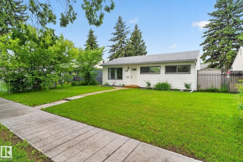 White exterior residence featuring a gray shingle roof, dark-trimmed windows, and a concrete sidewalk - 12952 114 Street Nw, Edmonton, AB 