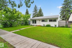 White exterior residence featuring a gray shingle roof, dark-trimmed windows, and a concrete sidewalk - 