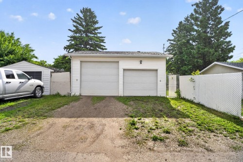 Detached garage with two roll-up doors, white vinyl siding, and an asphalt shingle roof - 12952 114 Street Nw, Edmonton, AB 