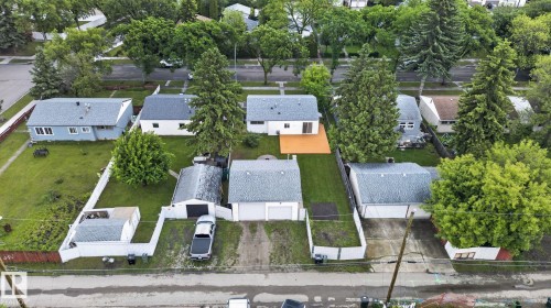 Residential property featuring a detached double garage with a paved driveway, a separate shed, and a fenced backyard - 12952 114 Street Nw, Edmonton, AB 