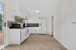 Kitchen featuring white cabinetry, dark countertops, a gray mosaic tile backsplash, and light-toned tile flooring - 
