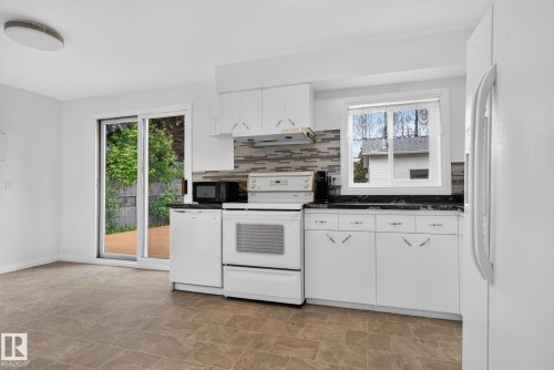 Kitchen space featuring white cabinetry, dark countertops, and a tiled backsplash - 12952 114 Street Nw, Edmonton, AB 