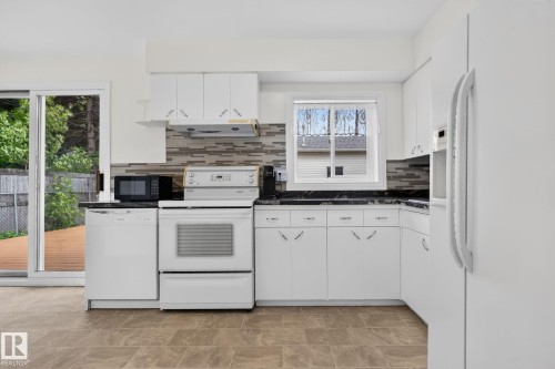 Kitchen featuring white cabinetry, dark countertops, and a tiled backsplash - 12952 114 Street Nw, Edmonton, AB 