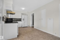 Functional kitchen featuring white cabinetry, a mosaic tile backsplash, black countertops, and a white side-by-side refrigerator - 