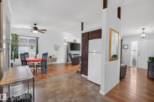 Bright interior featuring a white paneled front door with sidelight, wood-finish flooring, and white walls - 10935 152 Street, Edmonton, AB 