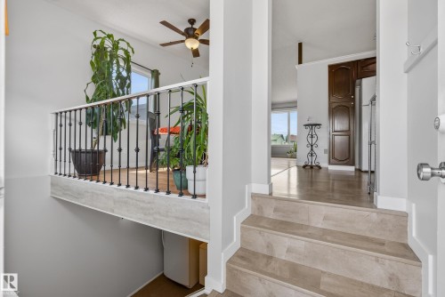 Split-level entry featuring wood-finish flooring and a decorative wrought iron railing - 10935 152 Street, Edmonton, AB 