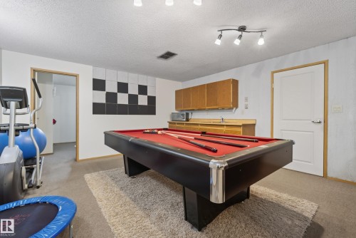Recreation room featuring a pool table, track lighting, and a built-in wet bar with wood-finish cabinetry and a sink - 10935 152 Street, Edmonton, AB 
