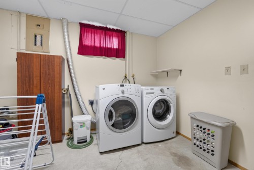 Dedicated laundry area featuring a front-loading washer and dryer, drop ceiling, and a visible electrical panel - 10935 152 Street, Edmonton, AB 