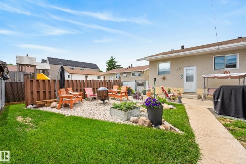 Private backyard featuring a concrete patio, a pea gravel seating area, a wood privacy fence, and a manicured lawn - 10935 152 Street, Edmonton, AB 
