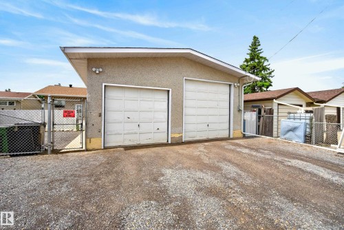 Detached two-car garage with two white panel garage doors, stucco exterior, and a gravel driveway - 10935 152 Street, Edmonton, AB 