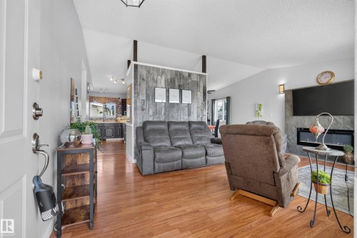 Open-concept living area with wood-finish flooring, vaulted ceilings, and a gray shiplap accent wall - 10935 152 Street, Edmonton, AB 