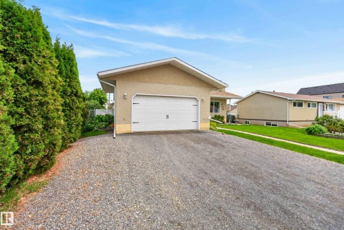 Gravel driveway leading to an attached garage with a white overhead door - 10935 152 Street, Edmonton, AB 