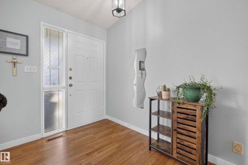 Entryway featuring wood-finish flooring, a white paneled door with a sidelight, and light gray wall paint - 10935 152 Street, Edmonton, AB 