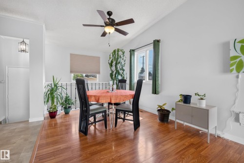 Open concept dining area featuring wood-finish flooring, a ceiling fan with integrated lighting, and a window with a roller blind - 10935 152 Street, Edmonton, AB 