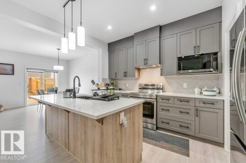 Modern kitchen featuring a large central island with wood-finish paneling and a light-toned countertop - 423 28 Street, Edmonton, AB 