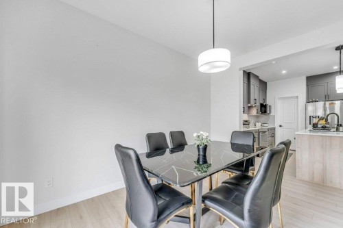 Dining area featuring wood-finish flooring and a contemporary pendant light fixture - 423 28 Street, Edmonton, AB 