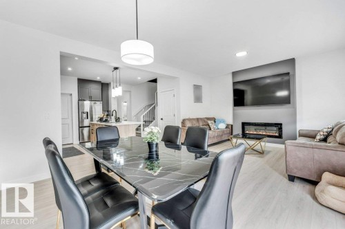 Open-concept living space featuring light wood-finish flooring, a built-in electric fireplace with a dark accent wall, and recessed lighting - 423 28 Street, Edmonton, AB 