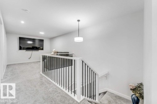 Upper level landing featuring carpeted flooring and a contemporary white handrail with black iron balusters - 423 28 Street, Edmonton, AB 