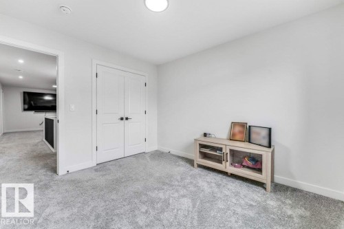 Light grey wall-to-wall carpeting, white interior doors with black hardware, and an overhead flush-mount light fixture - 423 28 Street, Edmonton, AB 