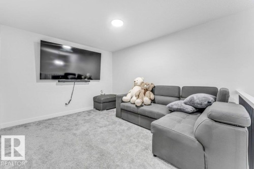 Carpeted media room with a wall-mounted display, recessed lighting, and white baseboards - 423 28 Street, Edmonton, AB 