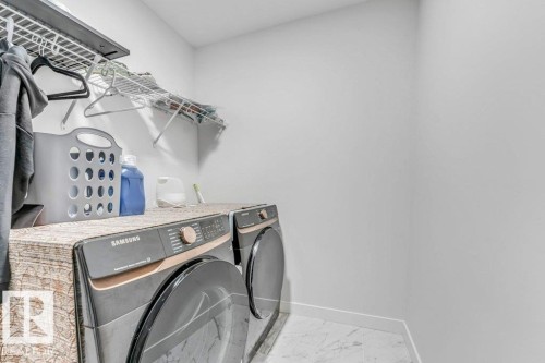 Dedicated laundry area featuring white walls, wire shelving, and light-toned tile flooring - 423 28 Street, Edmonton, AB 
