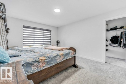 Bedroom featuring light gray carpeting, a large window with horizontal blinds, recessed ceiling lighting, white walls, and a walk-in closet with wire shelving and hanging rods - 423 28 Street, Edmonton, AB 