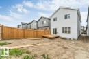 Rear exterior featuring a ground-level deck, white vinyl siding, and multiple windows - 423 28 Street, Edmonton, AB 