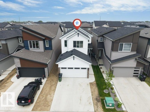 Contemporary white siding residence featuring a two-car garage, dark asphalt shingle roof, stone veneer accents, and a concrete driveway - 423 28 Street, Edmonton, AB 
