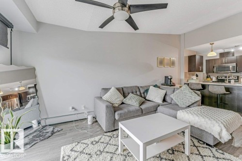 Open-concept living space with wood-finish flooring, a contemporary ceiling fan, and recessed lighting - 401 667 Watt Boulevard, Edmonton, AB 