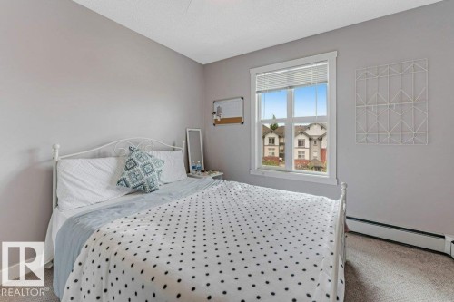 Light gray walls with a textured ceiling, a white-framed window, and gray carpet flooring - 401 667 Watt Boulevard, Edmonton, AB 