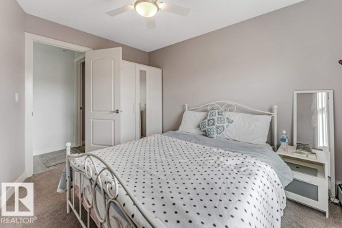 Bedroom featuring a ceiling fan with integrated lighting, neutral wall paint, and plush carpet flooring - 401 667 Watt Boulevard, Edmonton, AB 