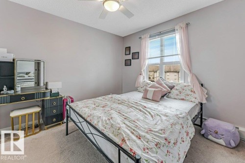 Carpeted bedroom featuring a ceiling fan with integrated lighting, a window with blinds, and a built-in wall heater - 401 667 Watt Boulevard, Edmonton, AB 