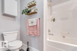 Full bathroom featuring a white toilet, white built-in wall cabinet, and a white tub/shower combination with a chrome faucet - 