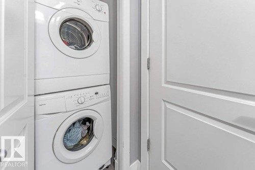 Compact laundry area featuring a stacked washer and dryer unit - 401 667 Watt Boulevard, Edmonton, AB 