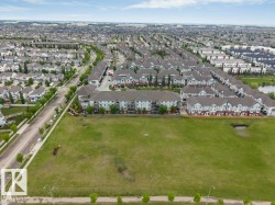 Expansive green space bordered by residential development and a street with mature trees - 