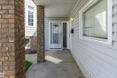 Covered front porch featuring brick columns, light-colored siding, and a white entry door with glass panels - 14707 33 Street, Edmonton, AB 