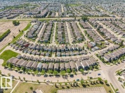 Aerial perspective of a developed residential neighborhood featuring a grid-patterned layout, curvilinear streets, and numerous detached homes - 